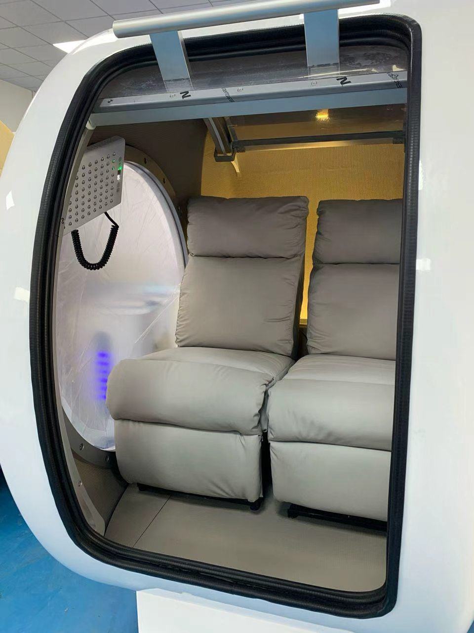 Modern vehicle interior with beige reclining seats and a window view.